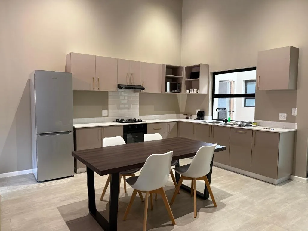 Modern kitchen with stove, refrigerator, cabinetry, and dining table