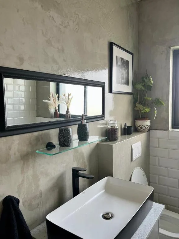 Modern bathroom with rectangular white sink, black mirror, and decorative potted plants