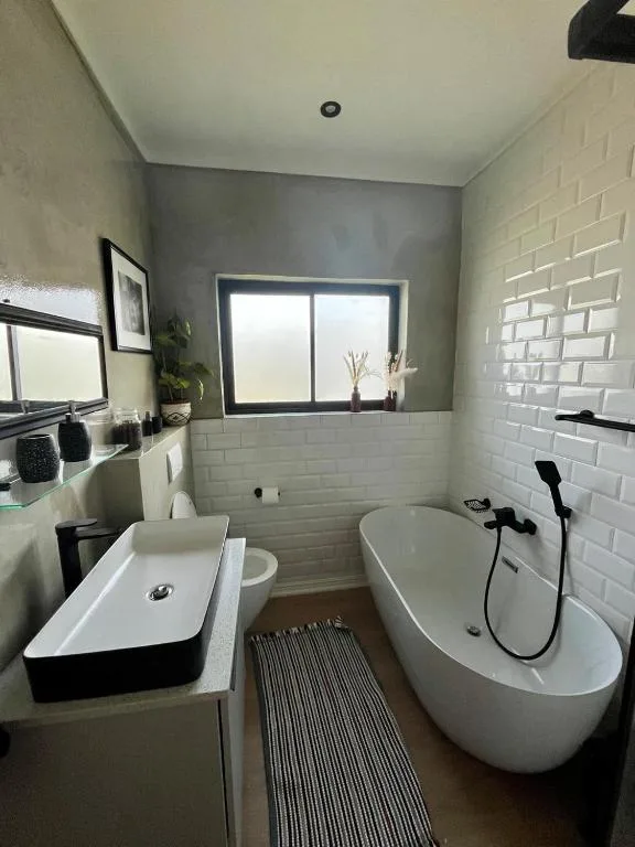 Modern bathroom with white subway tiles, freestanding bathtub, and vanity sink