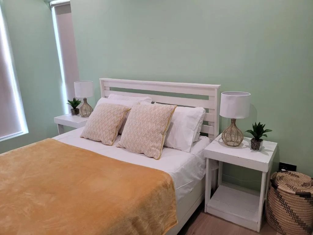 Bright bedroom with white bed frame, patterned pillows, and bedside tables with lamps