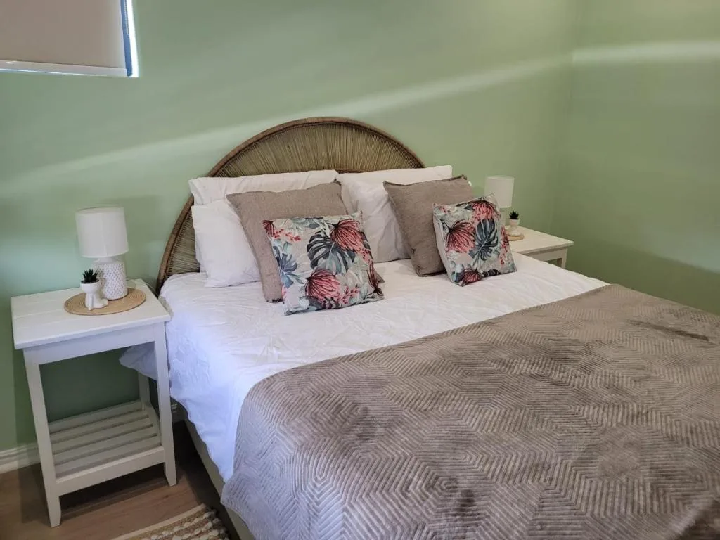 Serene bedroom with woven headboard, floral pillows, and mint green walls