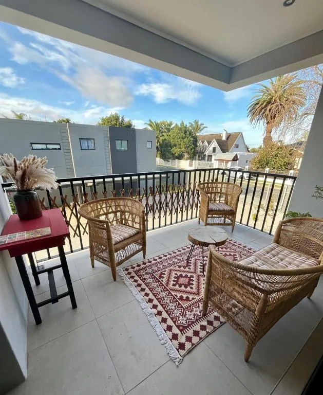 Covered balcony with wicker seating, decorative rug, and neighborhood views
