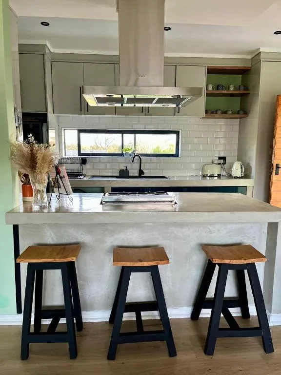 Modern kitchen with white subway tile backsplash, stainless steel range hood, and bar seating for three