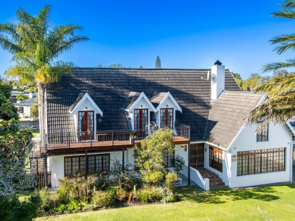 Modern white home with dark roof and palm trees in manicured garden