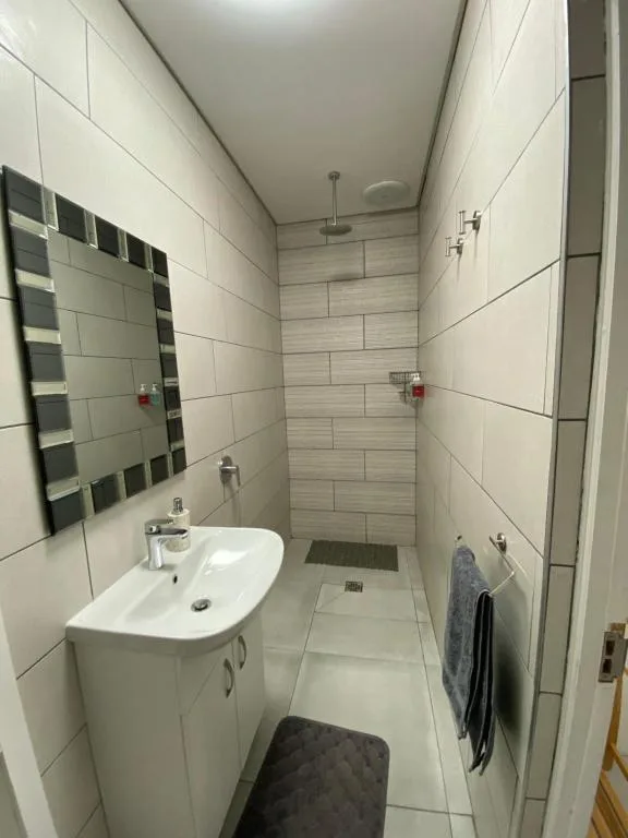 Modern bathroom with white vanity, mirror, and rainfall shower head
