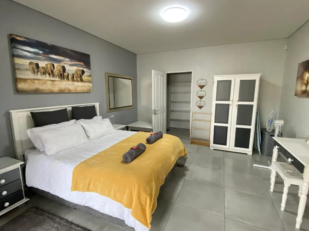 Spacious bedroom with queen bed, yellow throw, and modern furnishings