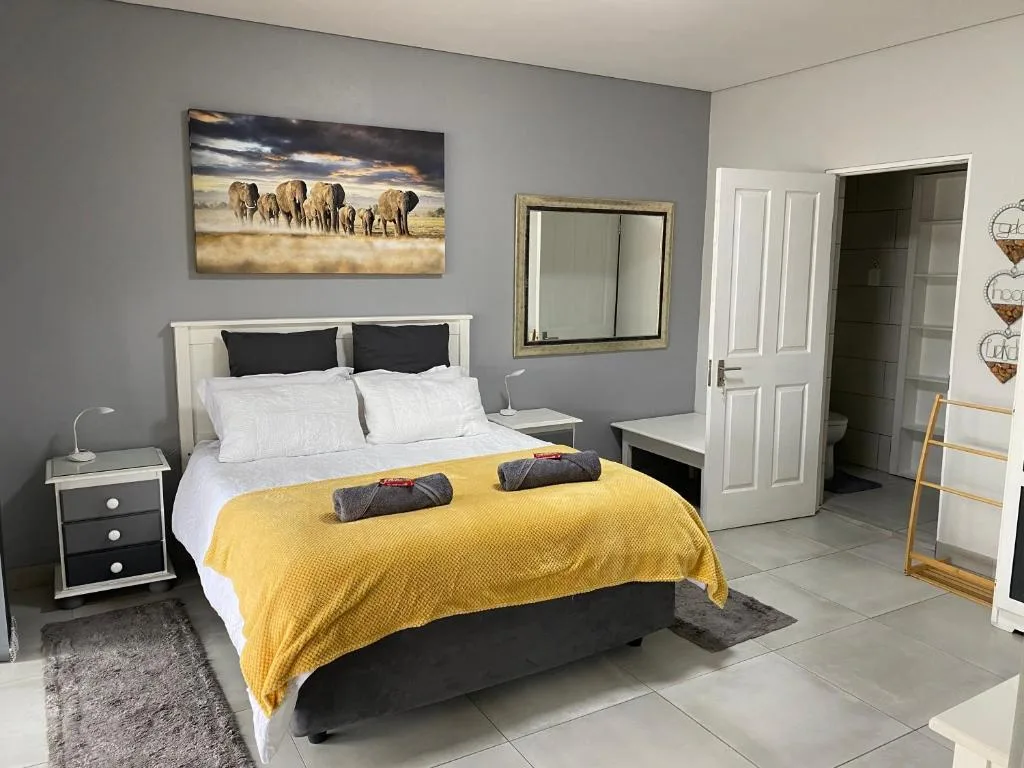 Modern bedroom with queen bed, yellow throw, and elephant artwork overhead