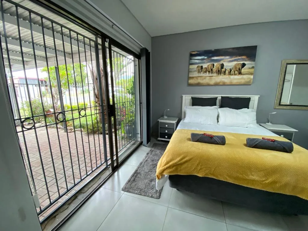 Bright bedroom with queen bed, yellow throw, and garden view doors