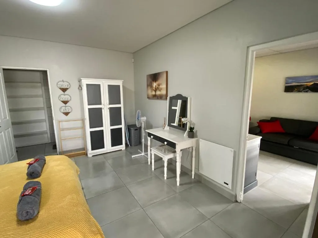 Bedroom with yellow bedspread, vanity desk, and open doorway to lounge area