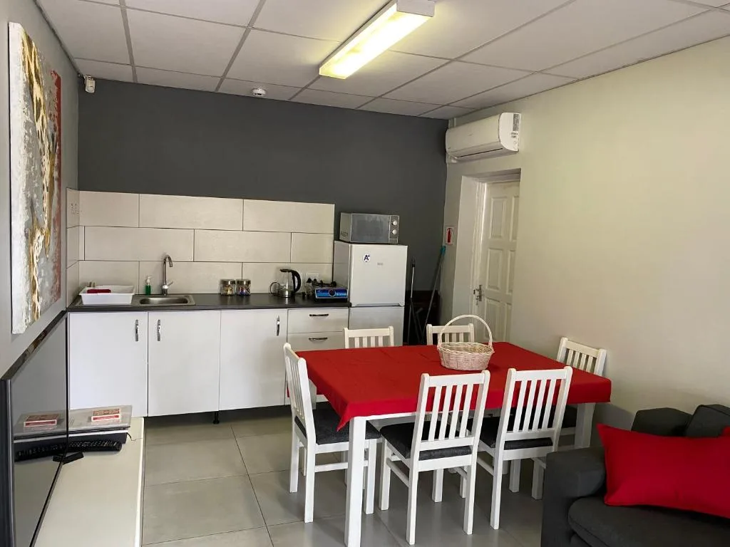 Open-plan kitchen and dining area with red table and white chairs