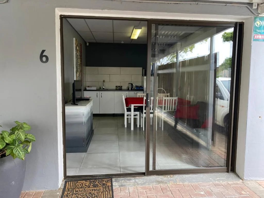 Modern apartment entrance with number 6, glass sliding doors, white cabinetry visible inside