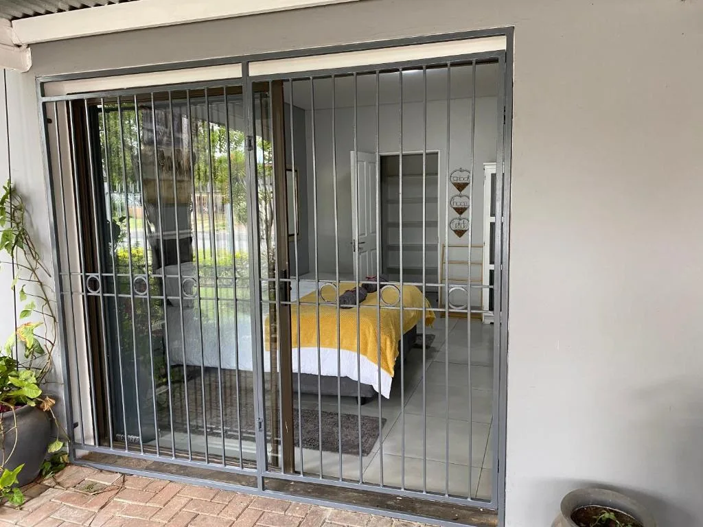Secured sliding glass doors opening onto bedroom with yellow bedding visible