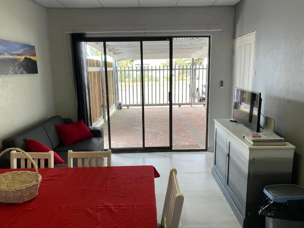 Open-plan lounge with sofa, dining table, and sliding glass doors to deck