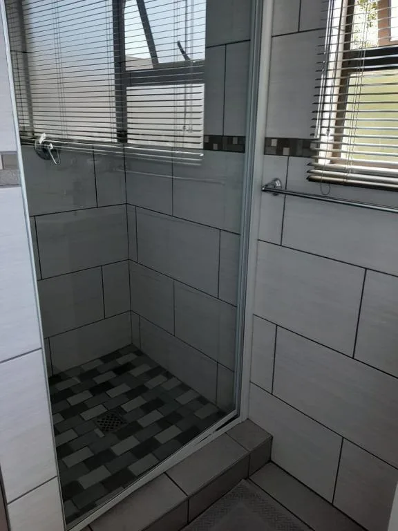 Modern shower enclosure with grey tile walls and geometric floor pattern