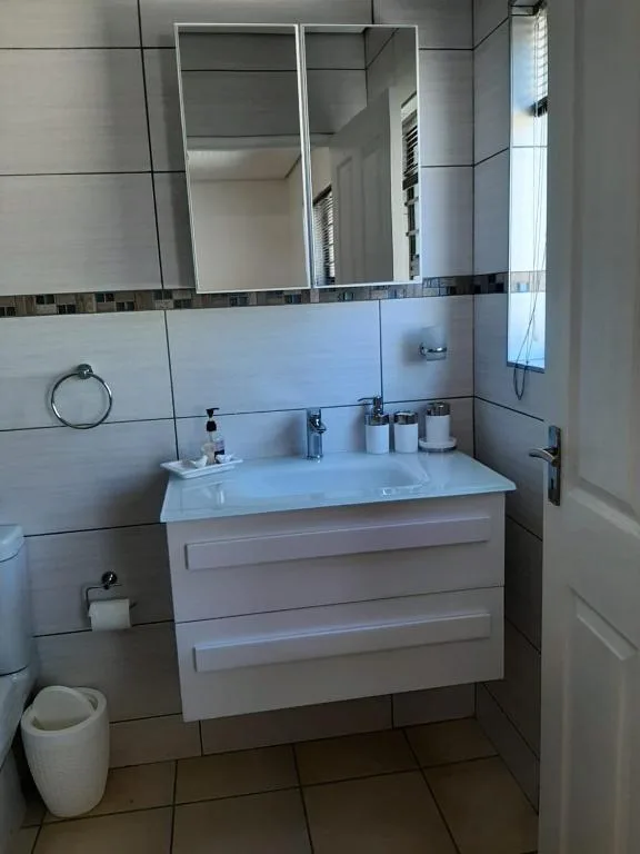 Modern bathroom with white vanity, mirror, and tiled walls