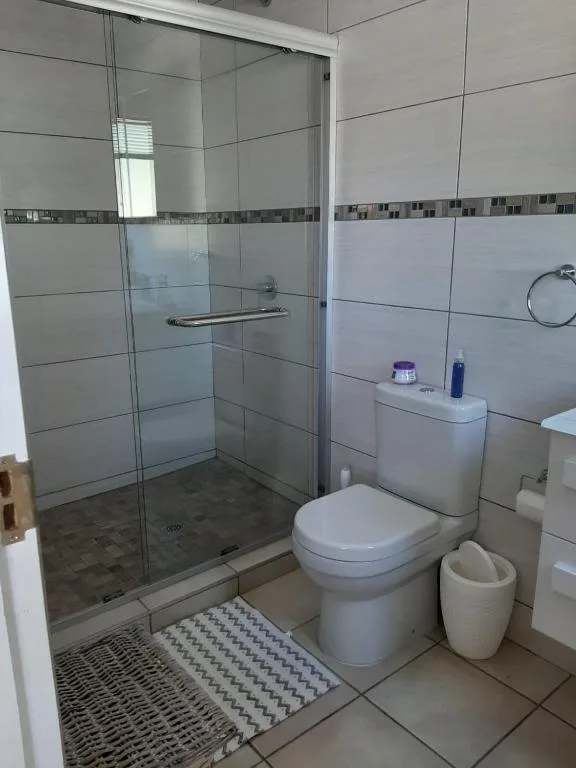 Modern bathroom with glass shower enclosure, toilet, and tiled walls