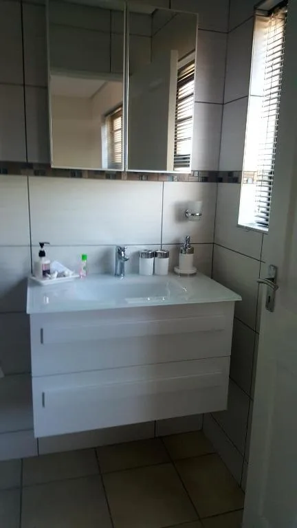 Modern bathroom with white vanity, large mirror, and tiled walls