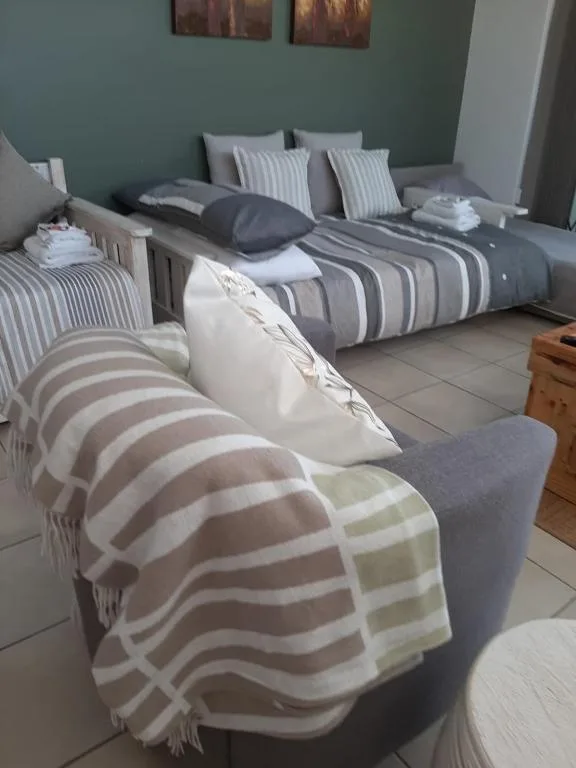 Spacious bedroom with two beds, striped bedding, sage green walls, and fresh linens