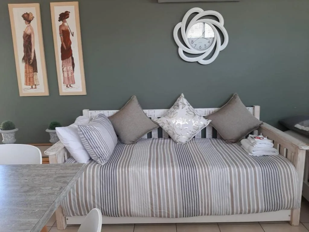 Neatly made bed with striped bedding and decorative cushions in modern bedroom