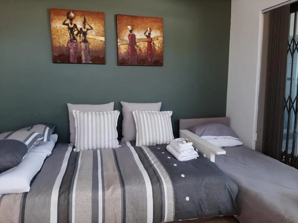 Modern bedroom with striped bedding, decorative pillows, and African-inspired artwork