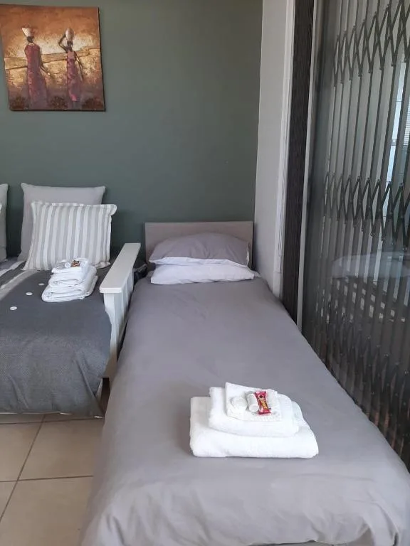 Bedroom with single beds, striped pillows, and framed artwork on wall