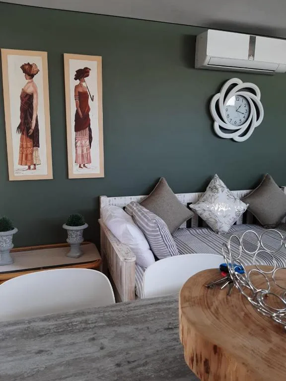 Modern bedroom with sage green walls, striped bedding, and artistic wall decor