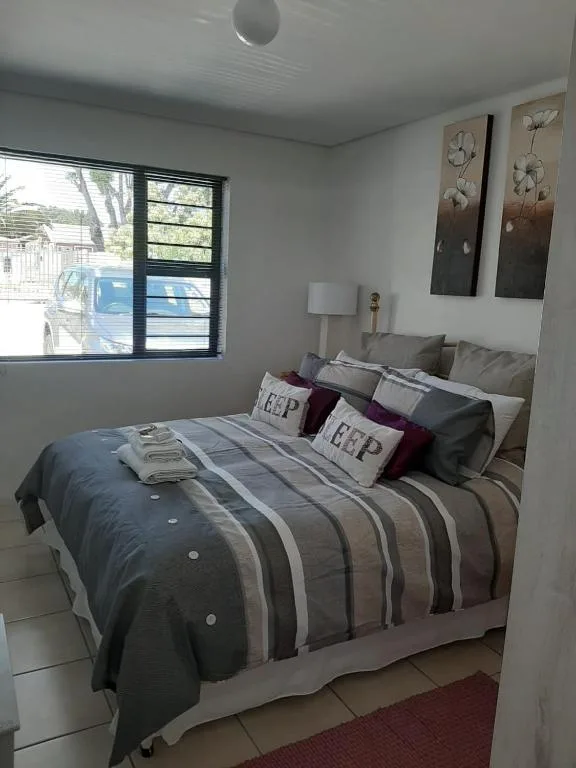Modern bedroom with striped duvet, decorative pillows, and window view