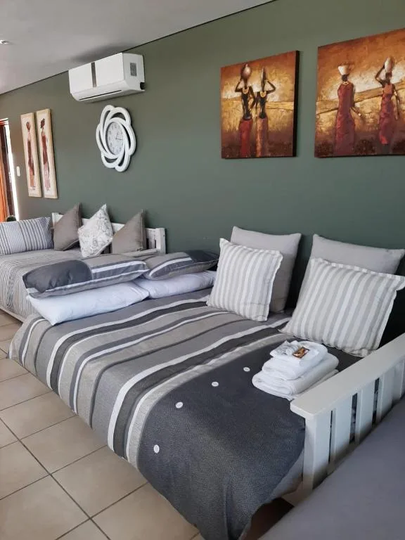 Spacious bedroom with two beds, striped bedding, sage green walls, and artwork