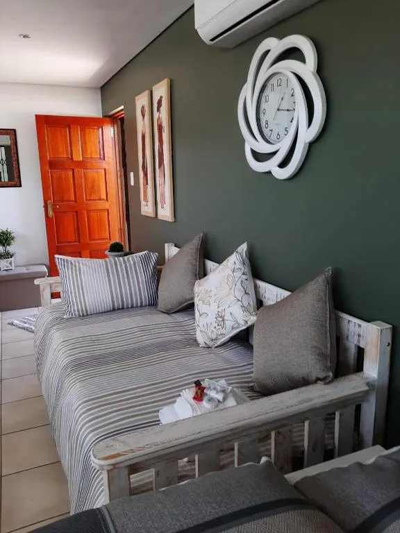 Cozy bedroom with striped bedding, decorative pillows, and sage green accent wall
