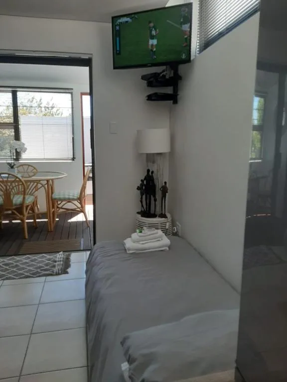 Modern bedroom with wall-mounted TV, bed, and open-plan lounge access