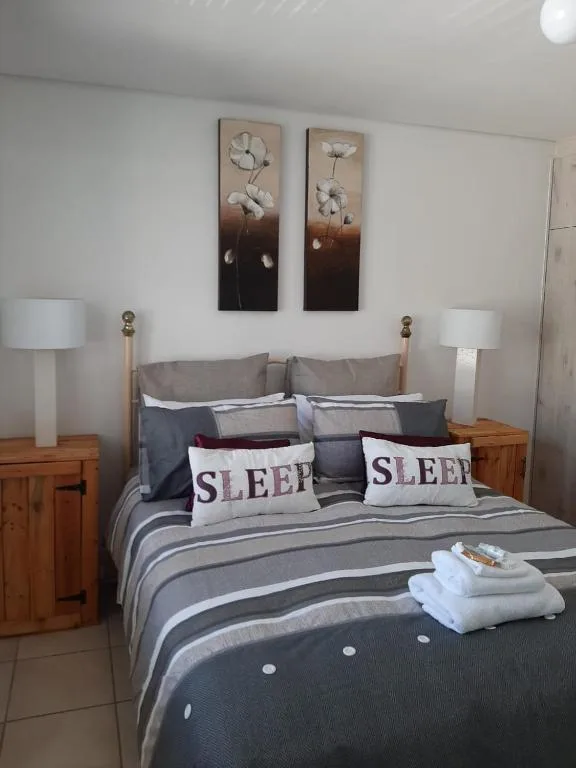 Bedroom with striped bedding, sleep pillows, wooden nightstands, and wall art