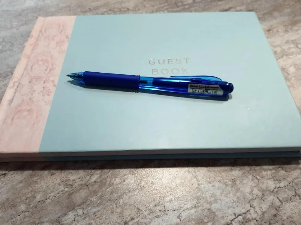 Guest book with blue pen on marble surface, property amenity