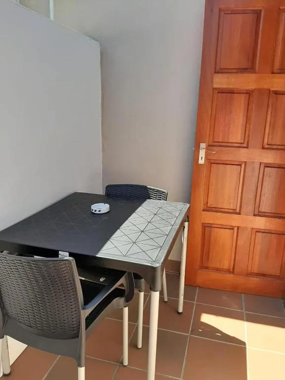 Compact dining table with woven chairs and wooden door entrance