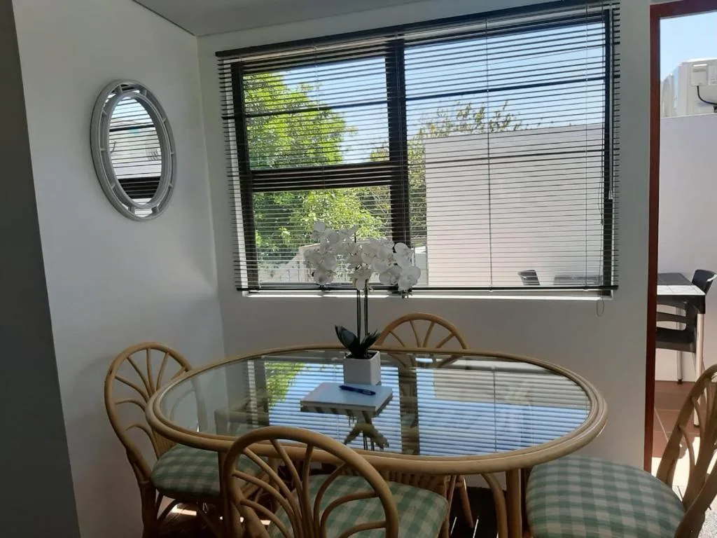 Bright dining area with oval glass table and rattan chairs near windows