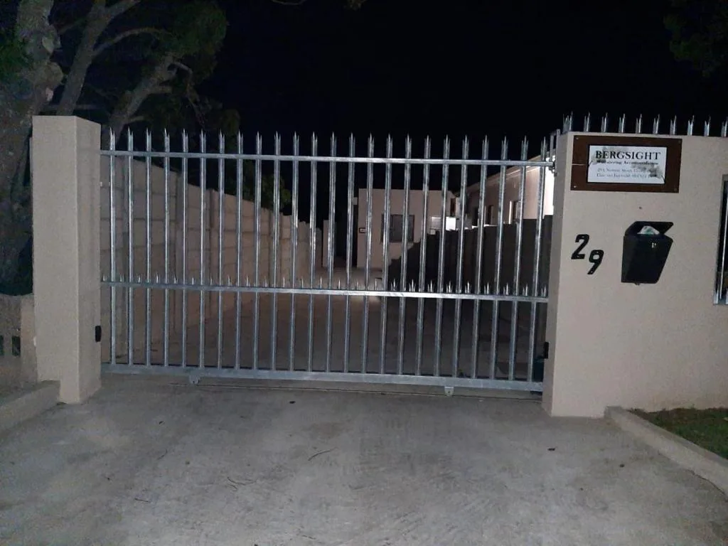 White metal security gate entrance to Bergsight accommodation property at night