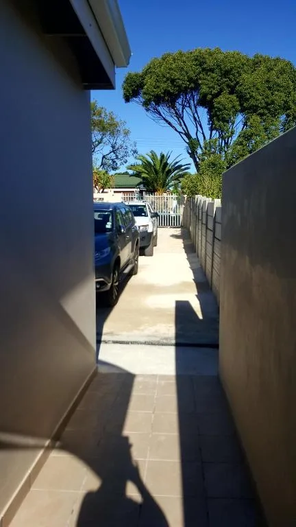 Narrow driveway with parked cars and mature trees beyond