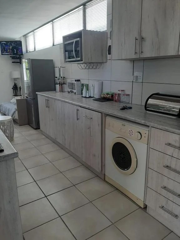 Modern kitchen with grey cabinetry, microwave, and washing machine appliance