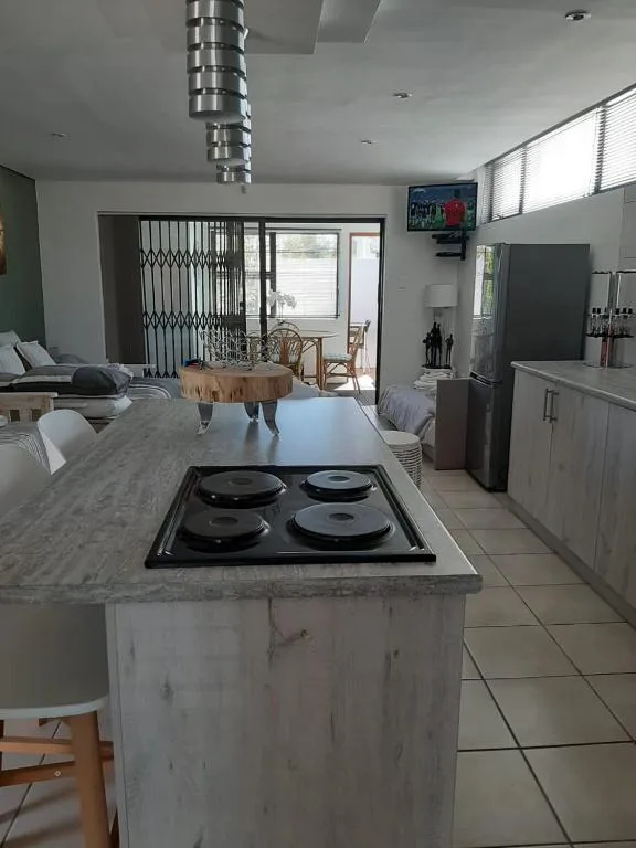 Modern open-plan kitchen with island cooktop, marble counters, stainless steel appliances