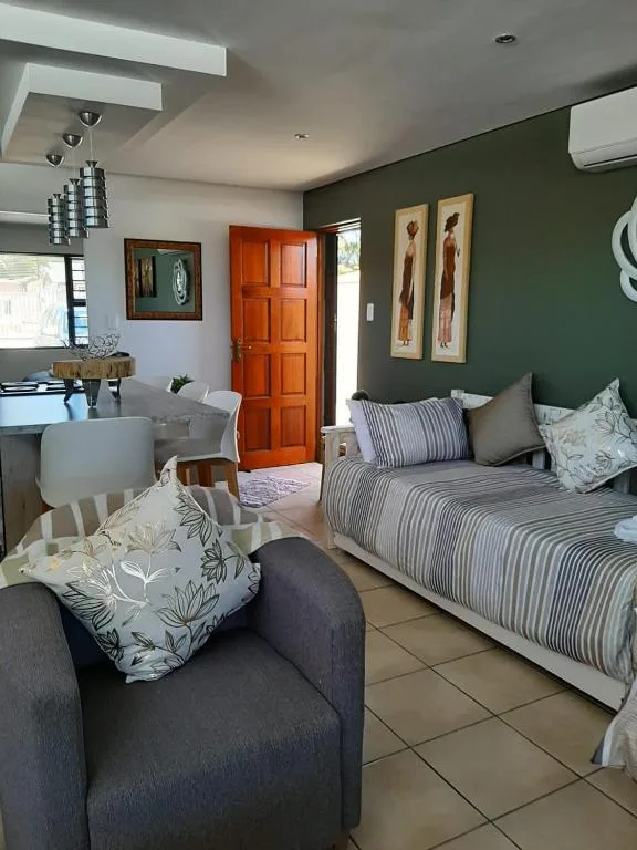 Modern lounge with grey armchair, striped bed, and green accent wall