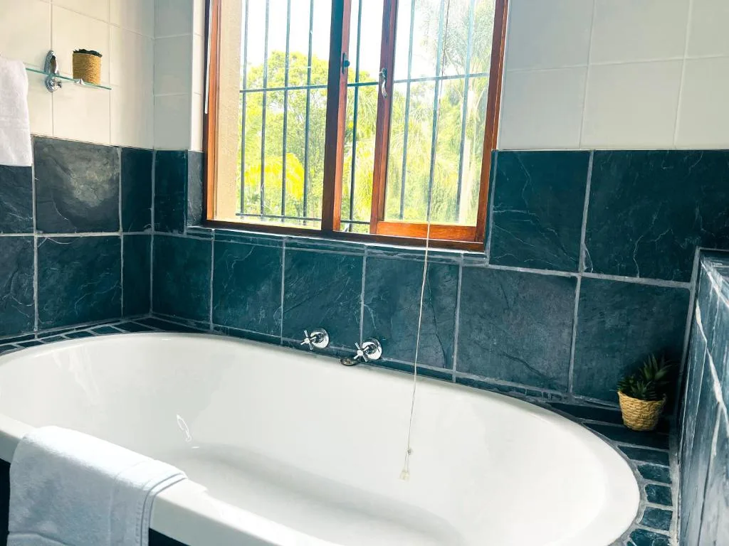 Modern bathroom with white freestanding tub and dark slate tile walls