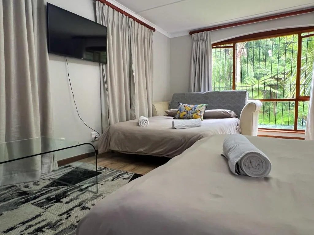 Bright bedroom with queen bed, twin beds, TV, and garden views