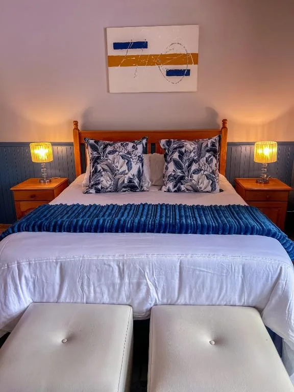 Modern bedroom with queen bed, decorative pillows, bedside lamps, and wall art