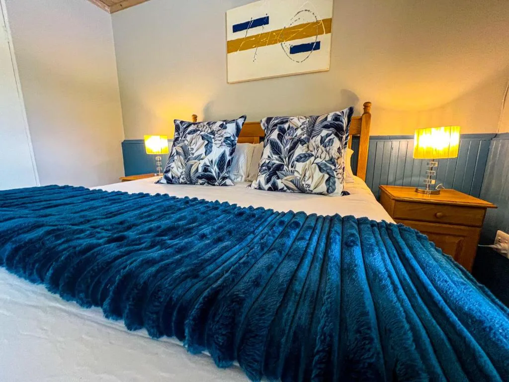 Bright bedroom with queen bed, decorative pillows, wooden nightstand, coastal artwork