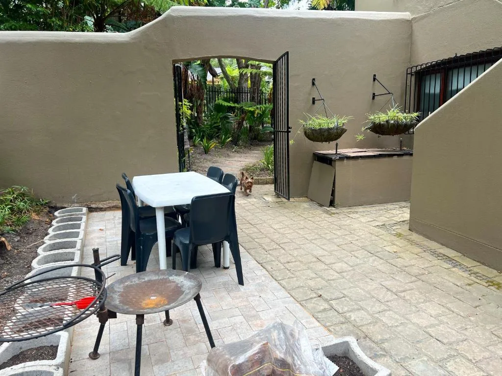 Paved outdoor patio with dining table, fire pit, and garden seating area