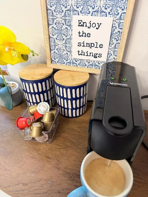 Coffee maker with inspirational sign and decorative storage containers on wooden table