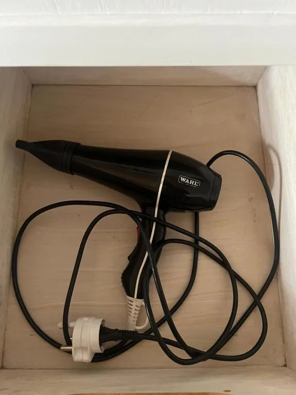 Black Wahl hair dryer with cord coiled in storage drawer