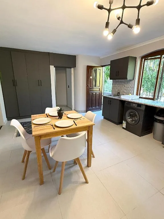 Open-plan dining and kitchen area with wooden table and white chairs