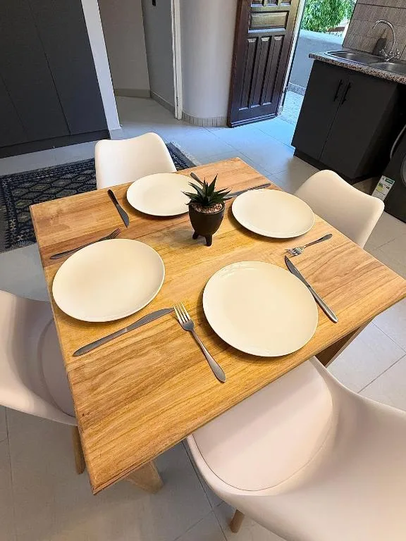 Wooden dining table set for four with white plates and cutlery