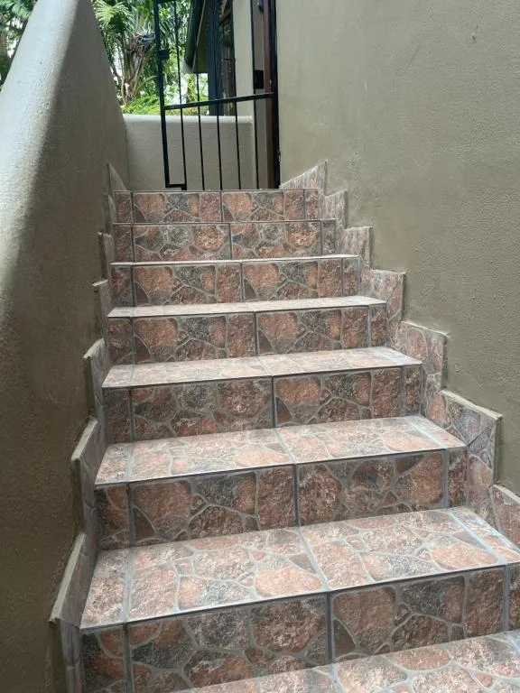 Tiled outdoor staircase with metal handrail leading to property entrance