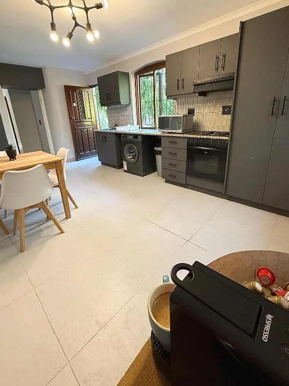 Modern kitchen with dark cabinetry, stainless steel appliances, and open dining area